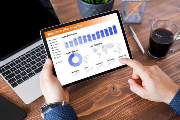 Streamline data entry with QuickBooks Man in office with data applications on laptop and iPad.